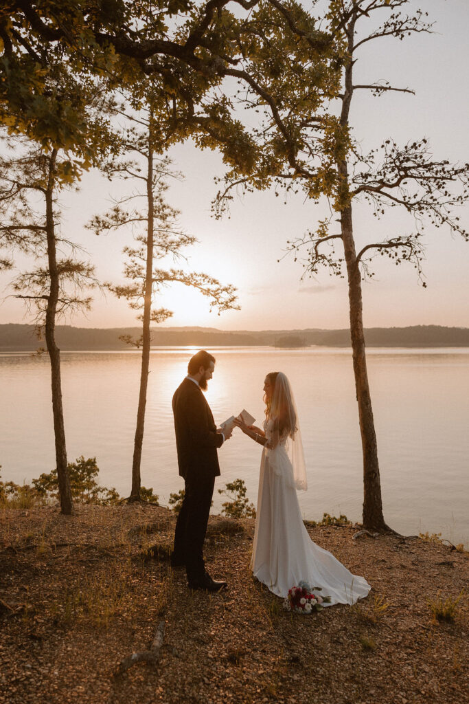 A couple reads their vows by a lake in Oklahoma as the sun sets