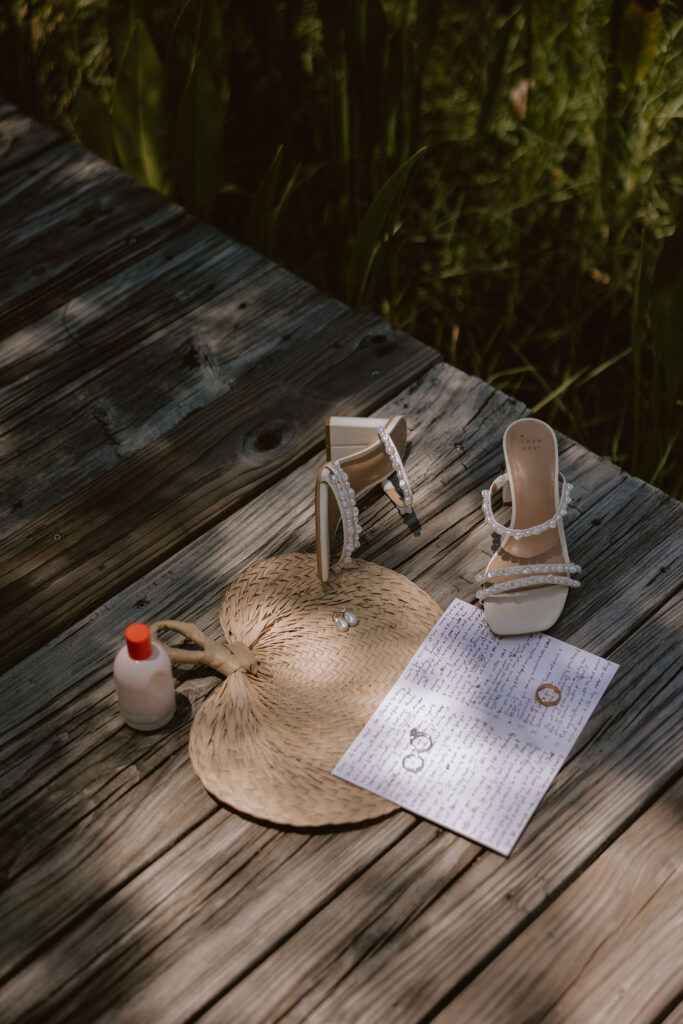 The brides details on a wood dock with the sunlight peeking through the foliage