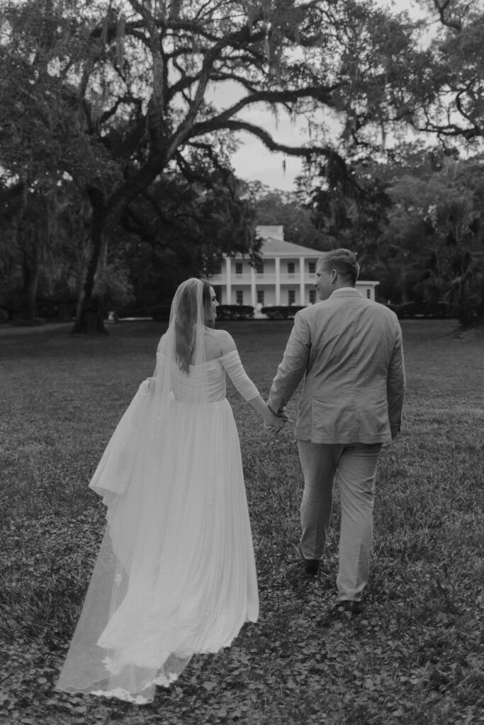 Bride and groom walk hand and hand through Eden Gardens state park