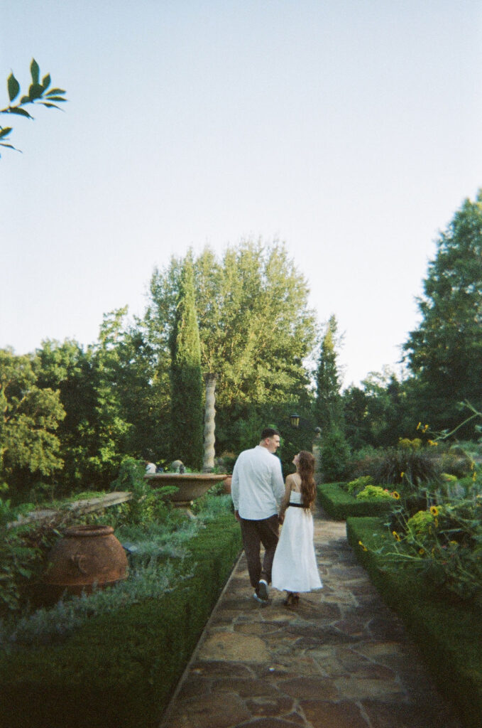 A 35 mm film shot of a couple walking through the gardens at Philbrook Museum of art for their engagement photos