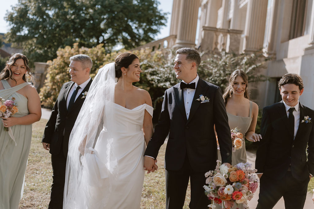 Bride and groom walk with their wedding party on the front lawn of Oklahoma Hall of Fame