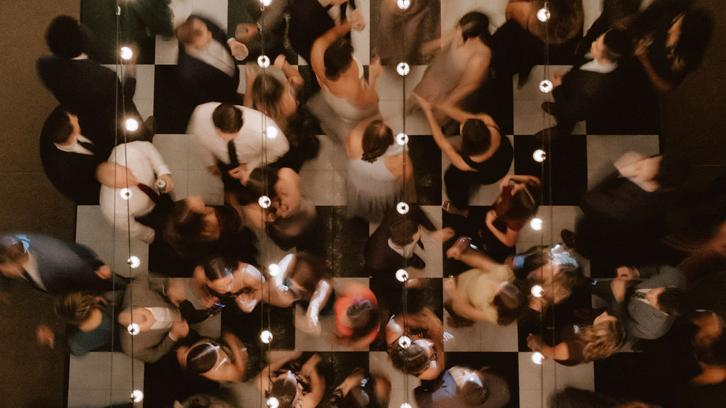 A lively wedding reception dance party on a checkered dance floor