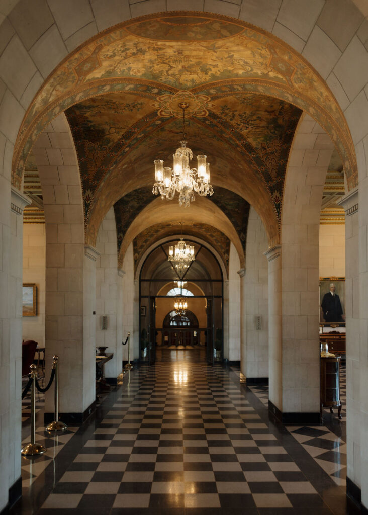 The interior of Marland Mansion with checkered floors, chandeliers, and arches