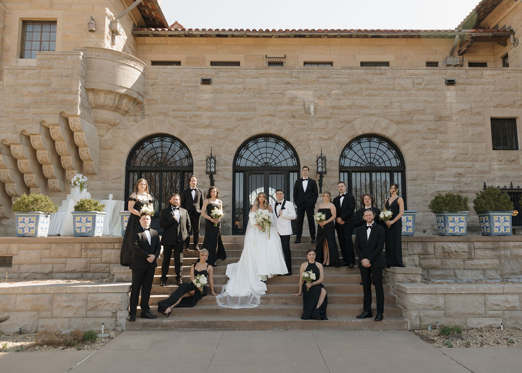 Bride and groom pose with their wedding party in front of Marland Mansion