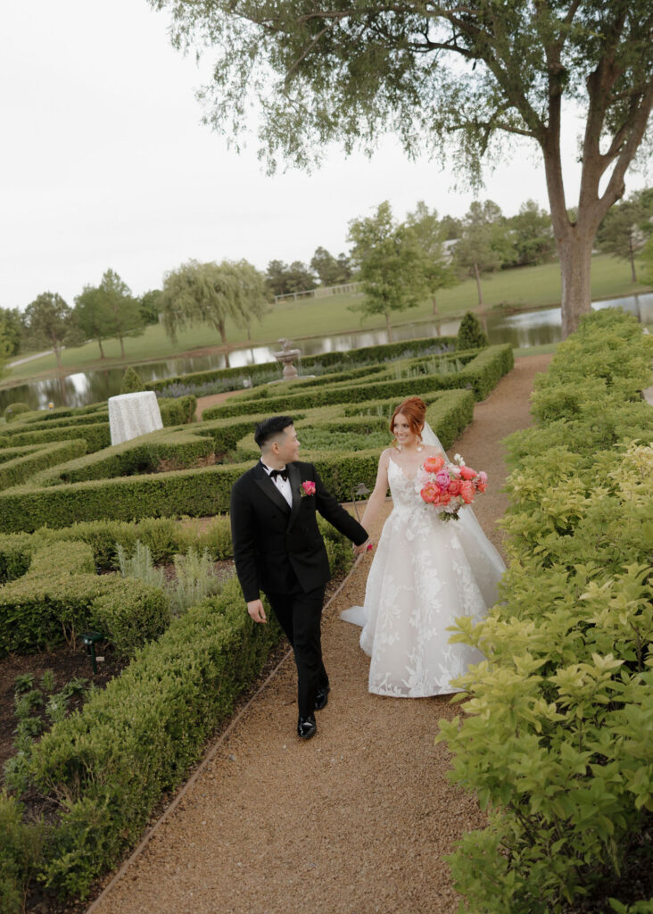 Bride and groom walk through the garden at The Bower Venue