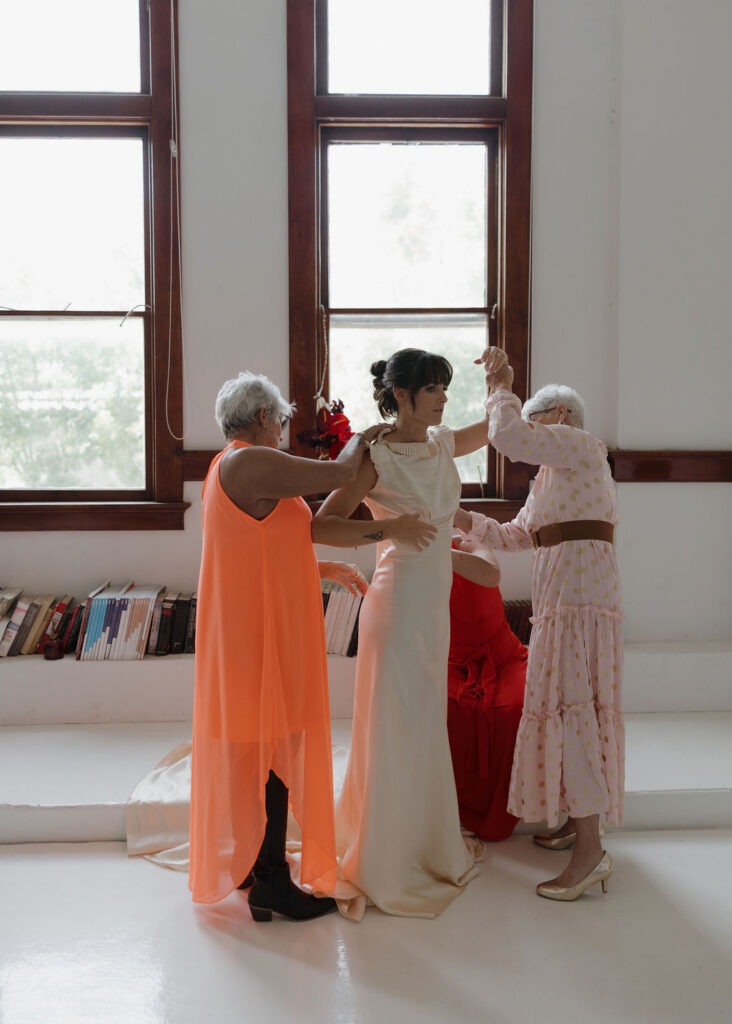 Bride gets help putting on her vintage wedding dress