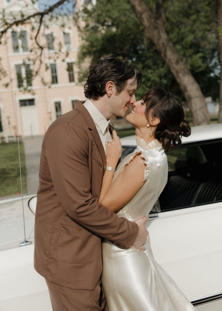 Bride and groom posing with old car in front of Marfa Courthouse
