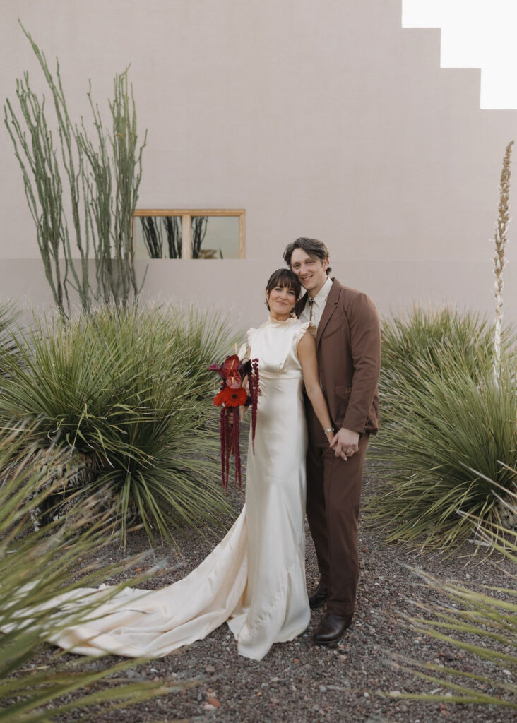 Bride and groom standing in desert foliage in Marfa, Texas
