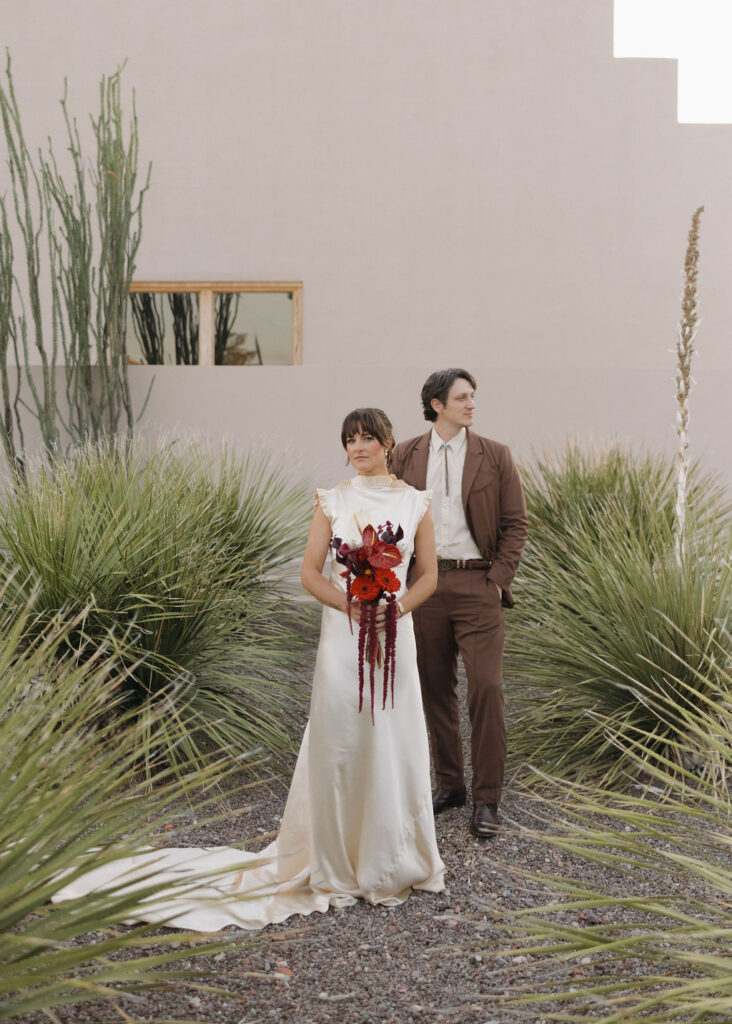 Bride and groom standing in desert foliage in Marfa, Texas