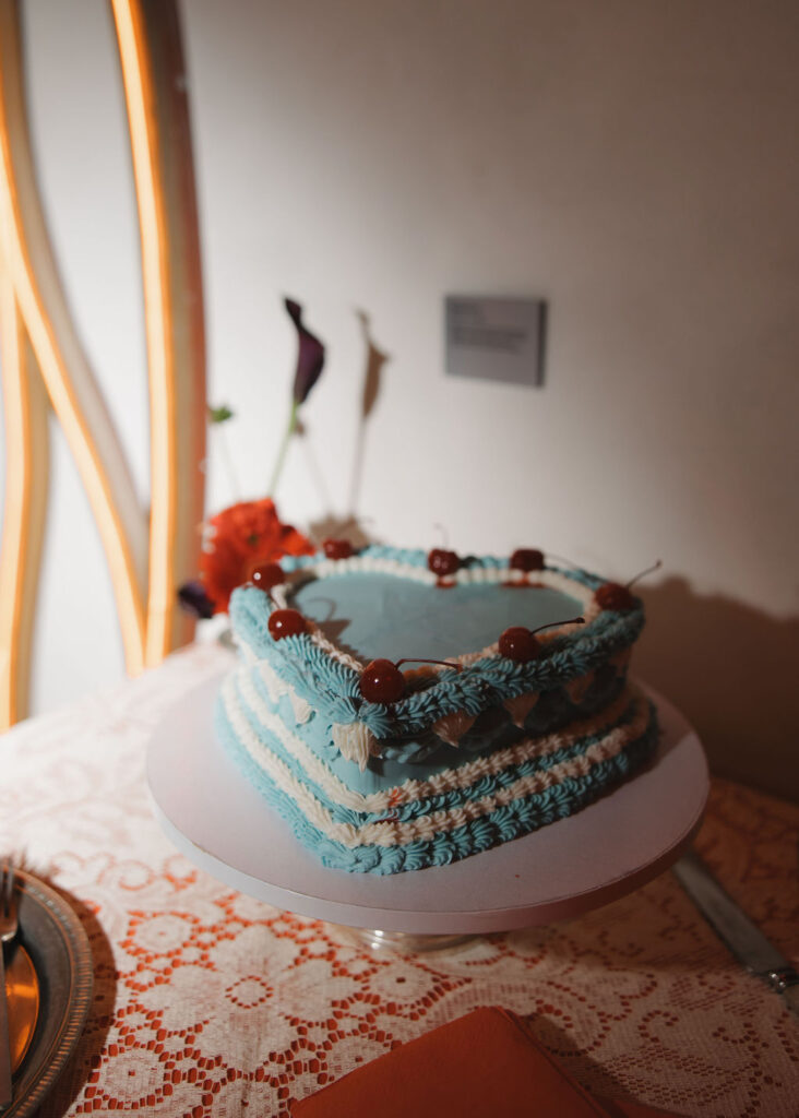 Blue heart shaped cake with white frosting details and cherries