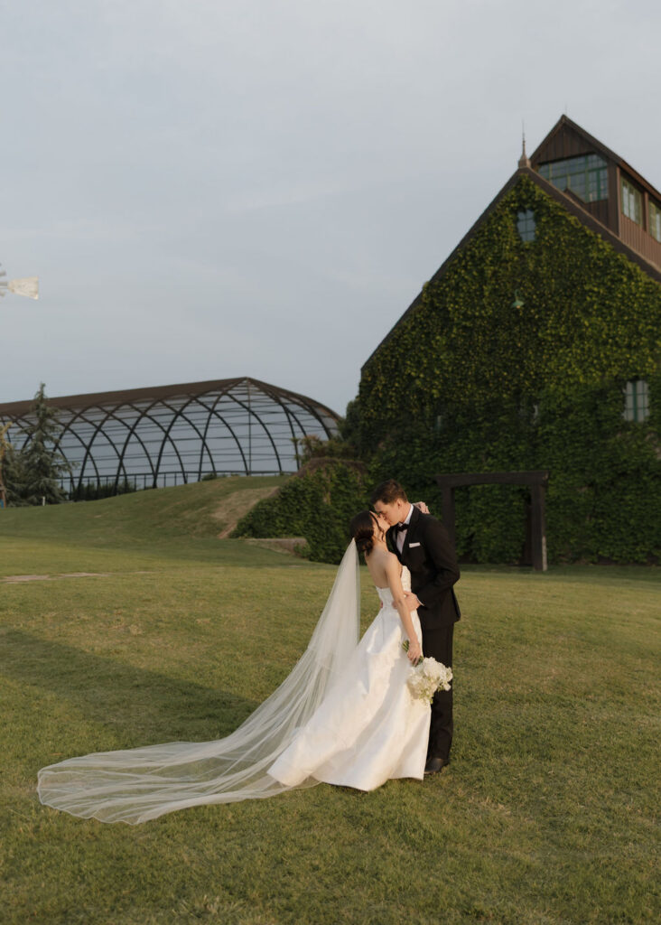 Bride and groom kiss on the lawn at The Baumberhof wedding venue at sunset